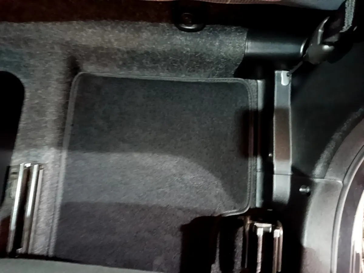 Vue du plancher côté conducteur de la Fiat 500 noire, montrant la moquette et les pédales en métal.