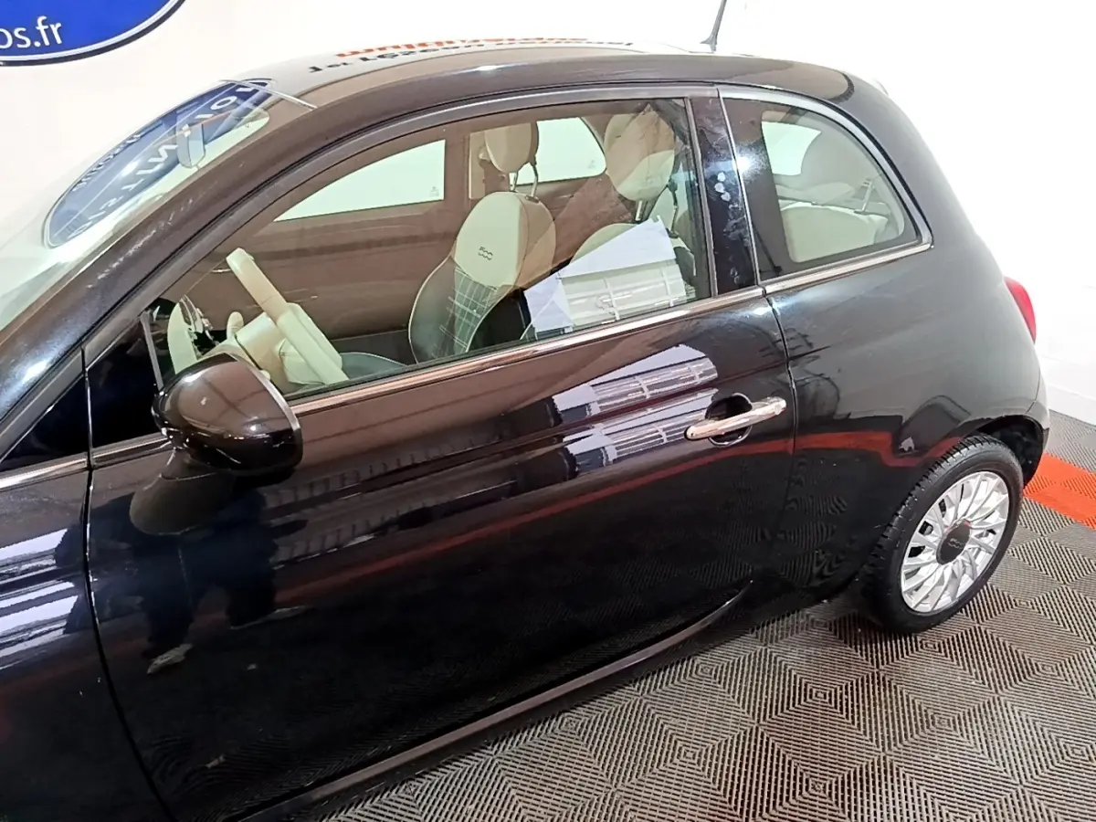 Vue de côté droit d'une FIAT 500 noire 2019 avec intérieur clair et jantes alliage distinctives.