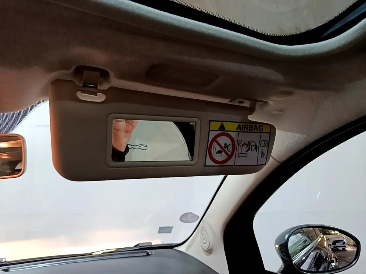 Détail du pare-soleil côté conducteur avec miroir et avertissement airbag dans l’habitacle d’une Fiat 500 noire.