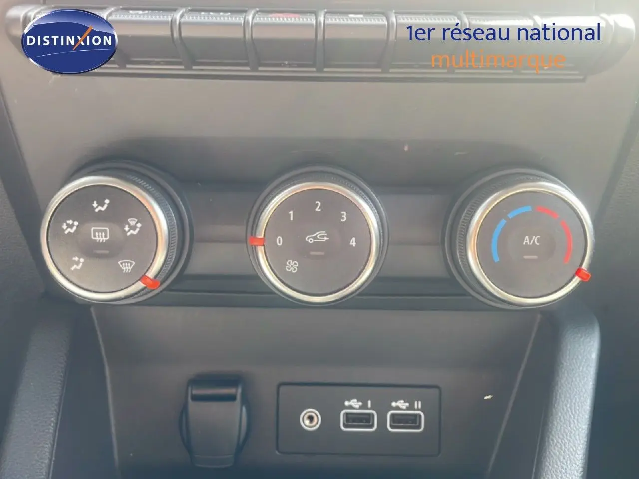 Gros plan sur les commandes de climatisation et les ports USB de la Renault Clio blanche, version Evolution 2025.