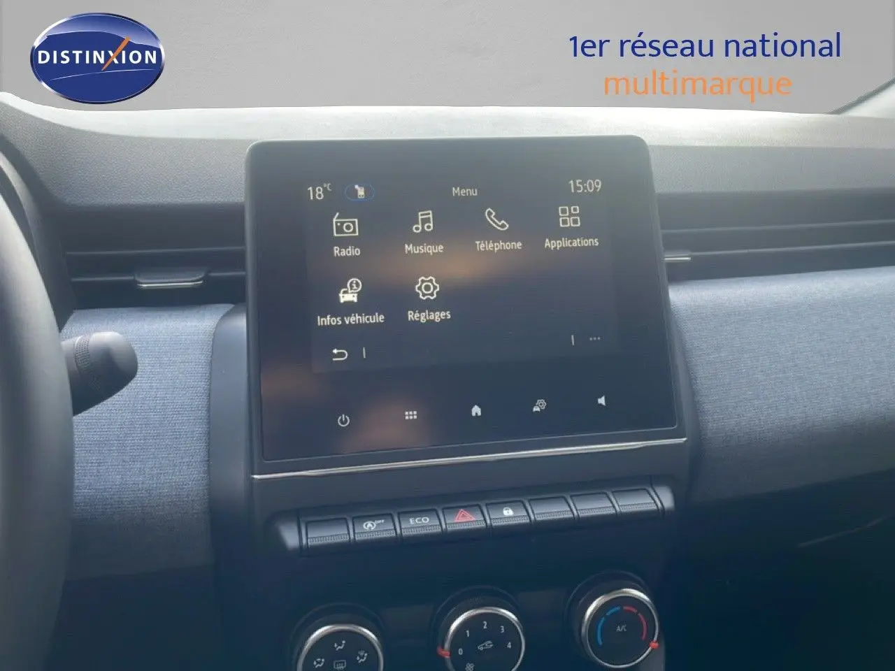 Vue intérieure centrée sur l'écran tactile du tableau de bord de la Renault Clio blanche 2025, avec commandes climatisation visibles.