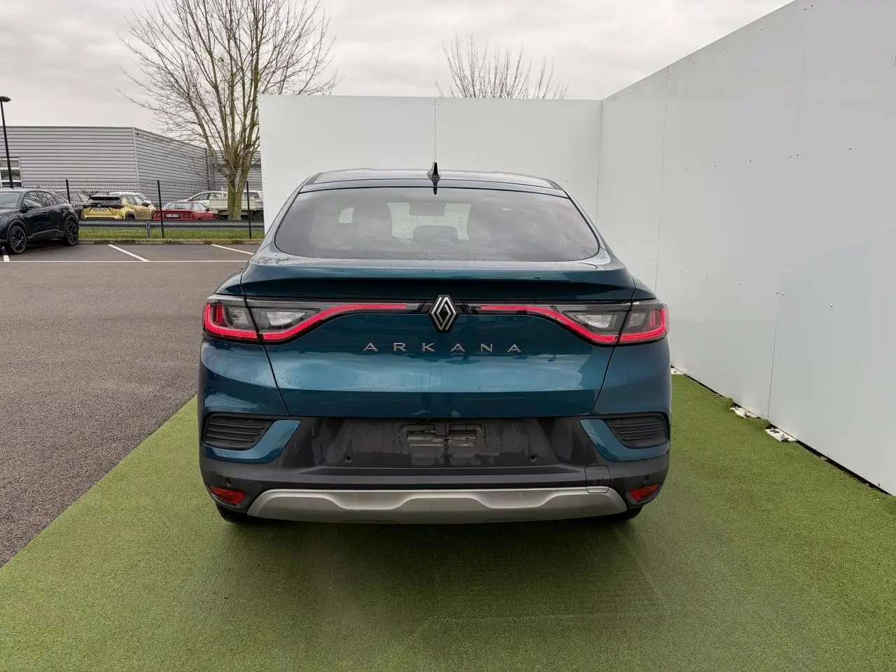 Vue arrière d'une Renault Arkana bleu Zanzibar métal avec feux LED reliés et lunette arrière surteintée.