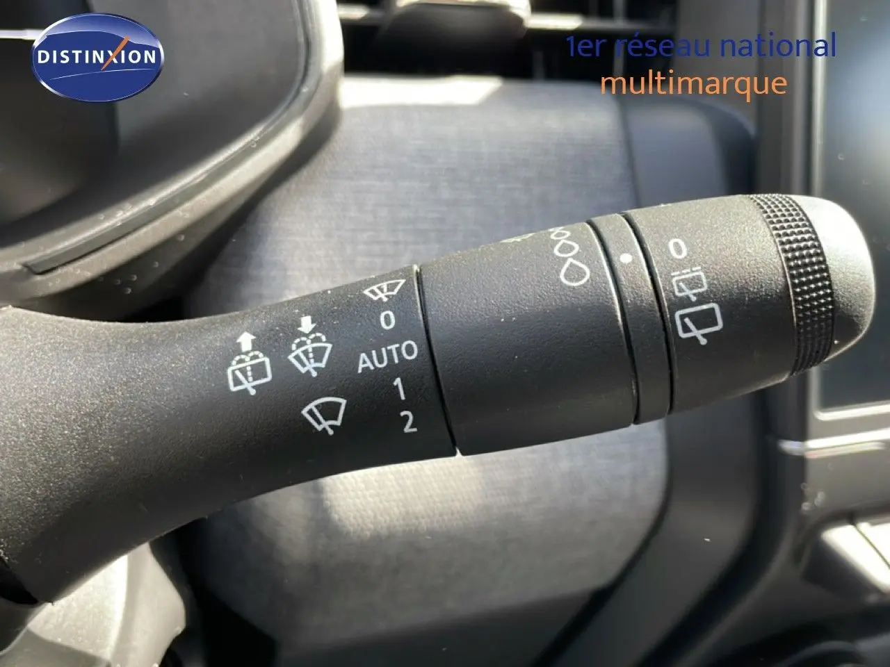 Gros plan sur la manette des essuie-glaces de la Renault Clio 2025, intérieur gris et noir avec commandes visibles.