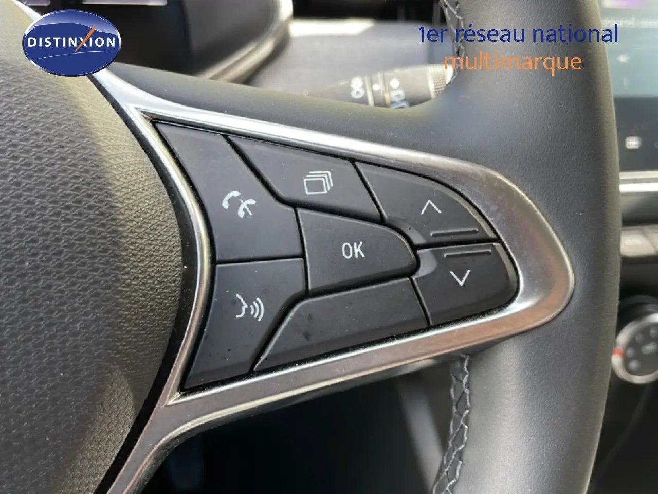 Gros plan sur les commandes multifonctions du volant en cuir noir de la Renault Clio gris schiste 2025, version Evolution.