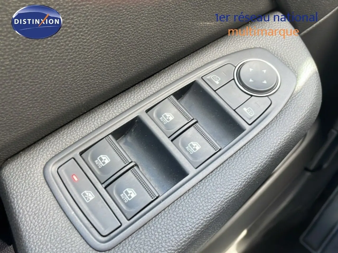 Gros plan sur les commandes des vitres électriques et rétroviseurs côté conducteur d'une Renault Clio gris schiste 2025.