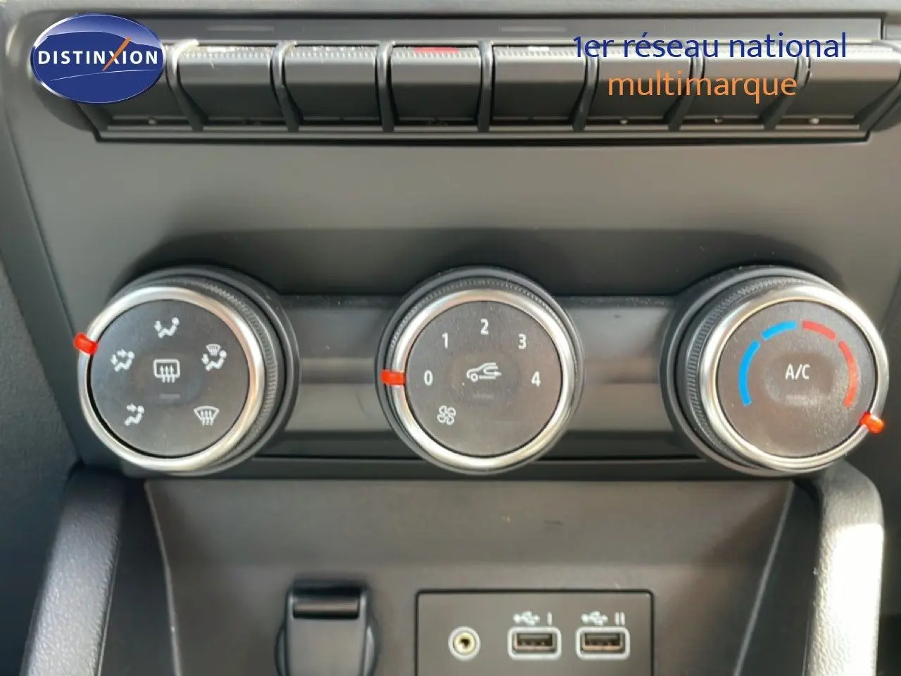 Gros plan sur les commandes de climatisation et les ports USB d’une Renault Clio gris schiste, intérieur moderne.