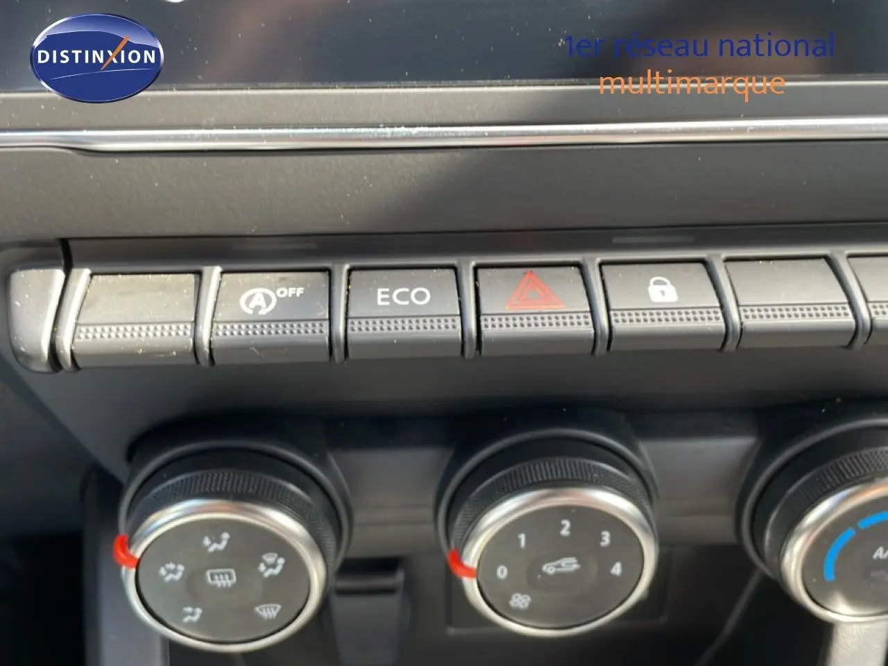 Vue rapprochée des commandes de climatisation et boutons de fonction sur la console centrale d’une Renault Clio gris schiste.