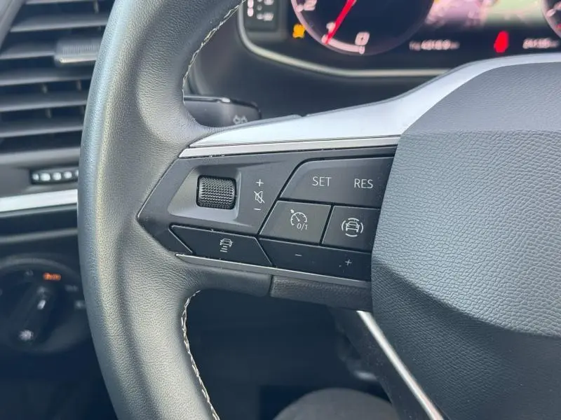 Gros plan sur les commandes gauche du volant cuir noir du SEAT Ateca 2024, avec boutons de régulateur de vitesse et assistance.