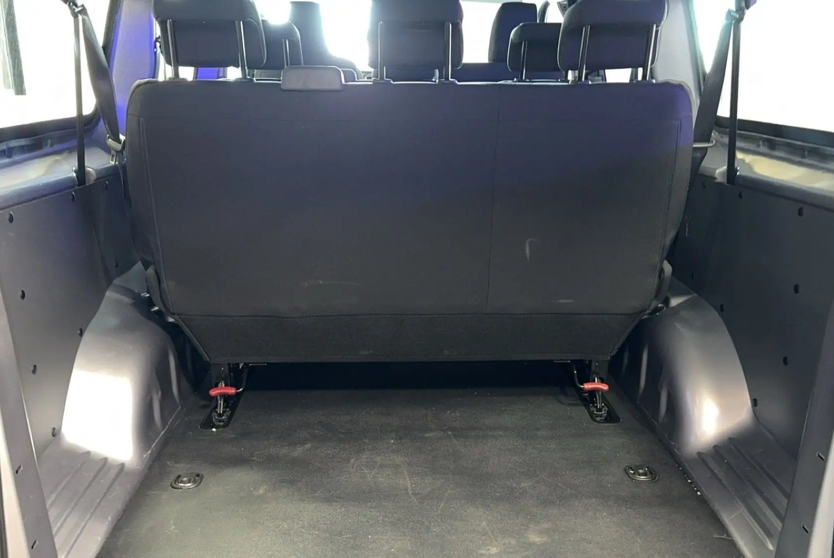 Vue arrière intérieure du coffre spacieux d'un Opel Vivaro Combi gris 2022 avec banquette arrière en tissu noir.