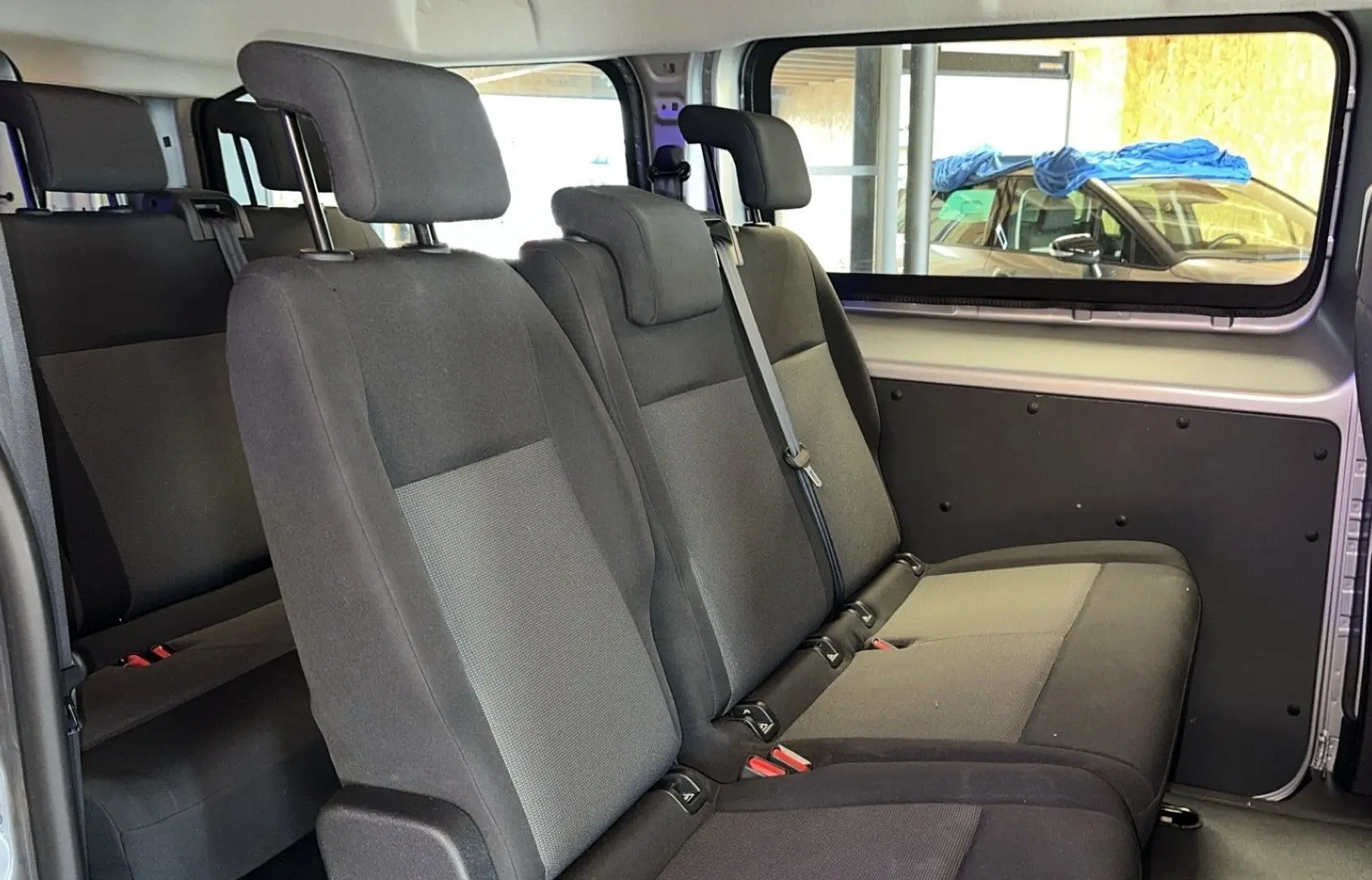 Vue intérieure des sièges en tissu gris foncé et clair à trois places du côté droit de l'Opel Vivaro Combi gris 2022.