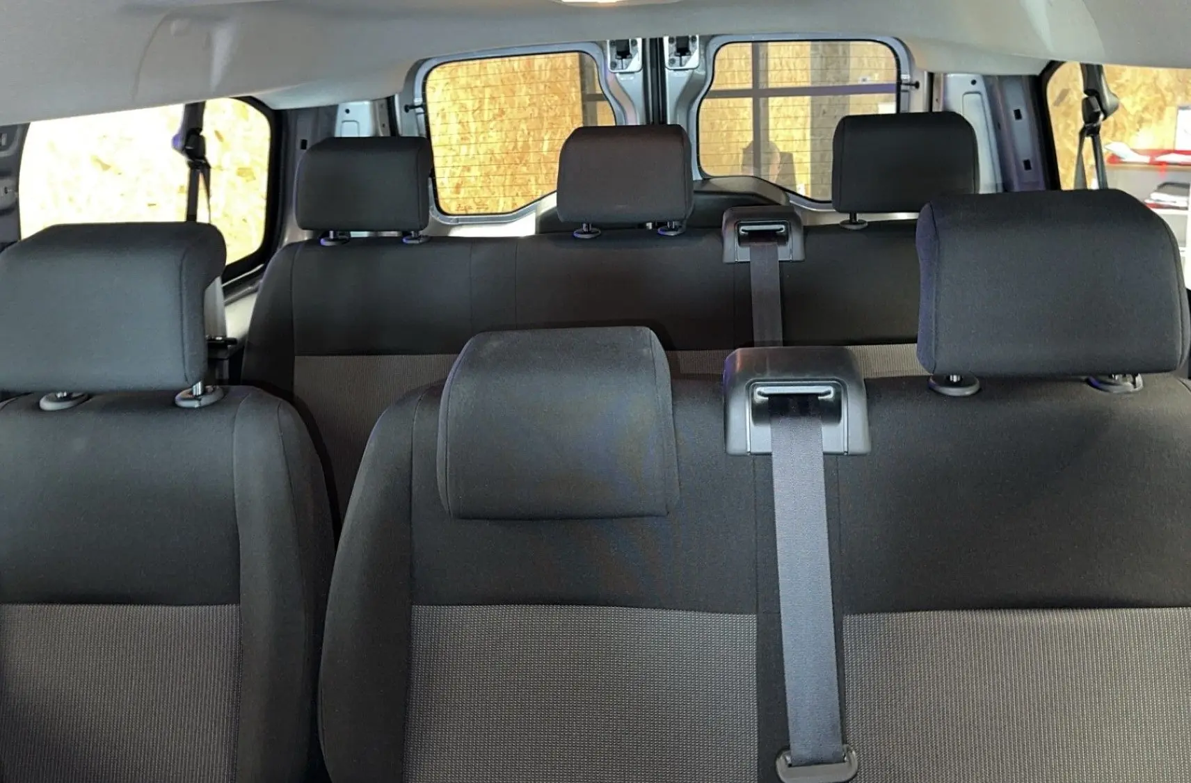 Vue intérieure des sièges en tissu noir et gris de l'Opel Vivaro Combi 2022, version diesel 1.5, avec ceintures visibles.