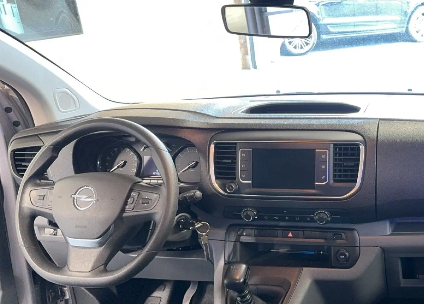 Intérieur de l'Opel Vivaro Combi gris 2022, vue frontale du tableau de bord avec volant multifonction et écran tactile éteint.