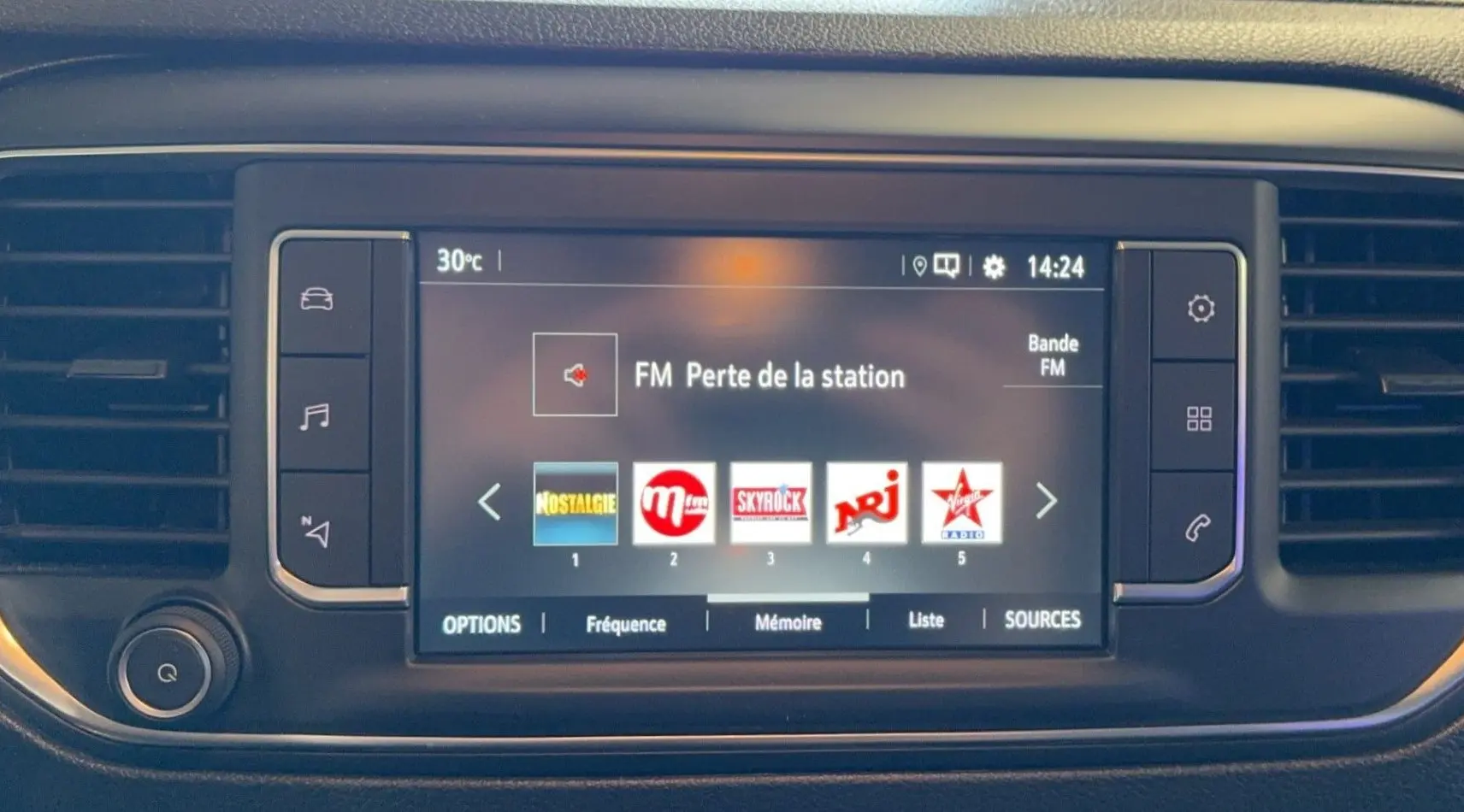 Écran tactile central du tableau de bord de l'Opel Vivaro Combi 2022 affichant les stations radio FM avec commandes latérales.