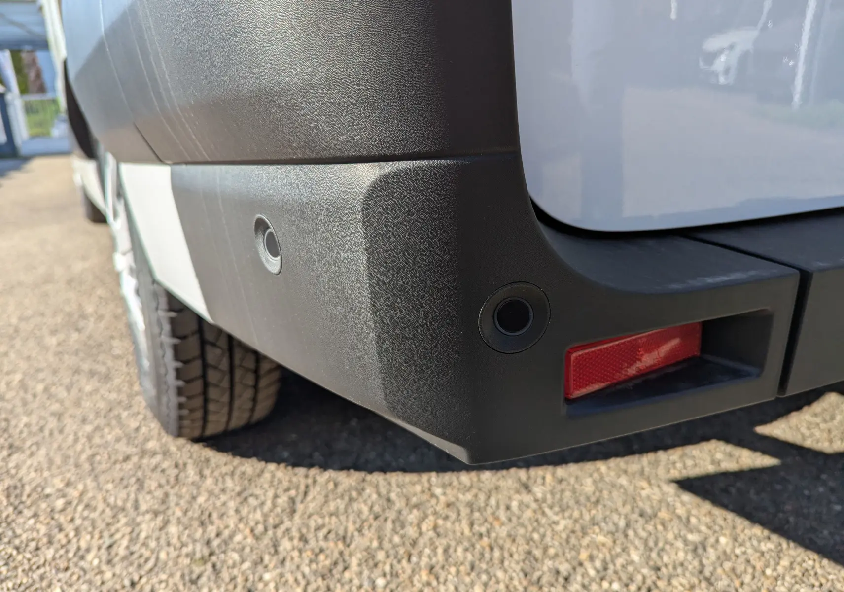 Gros plan sur le pare-chocs arrière droit blanc du Renault Master 2025 avec capteurs de recul et feu réfléchissant rouge.