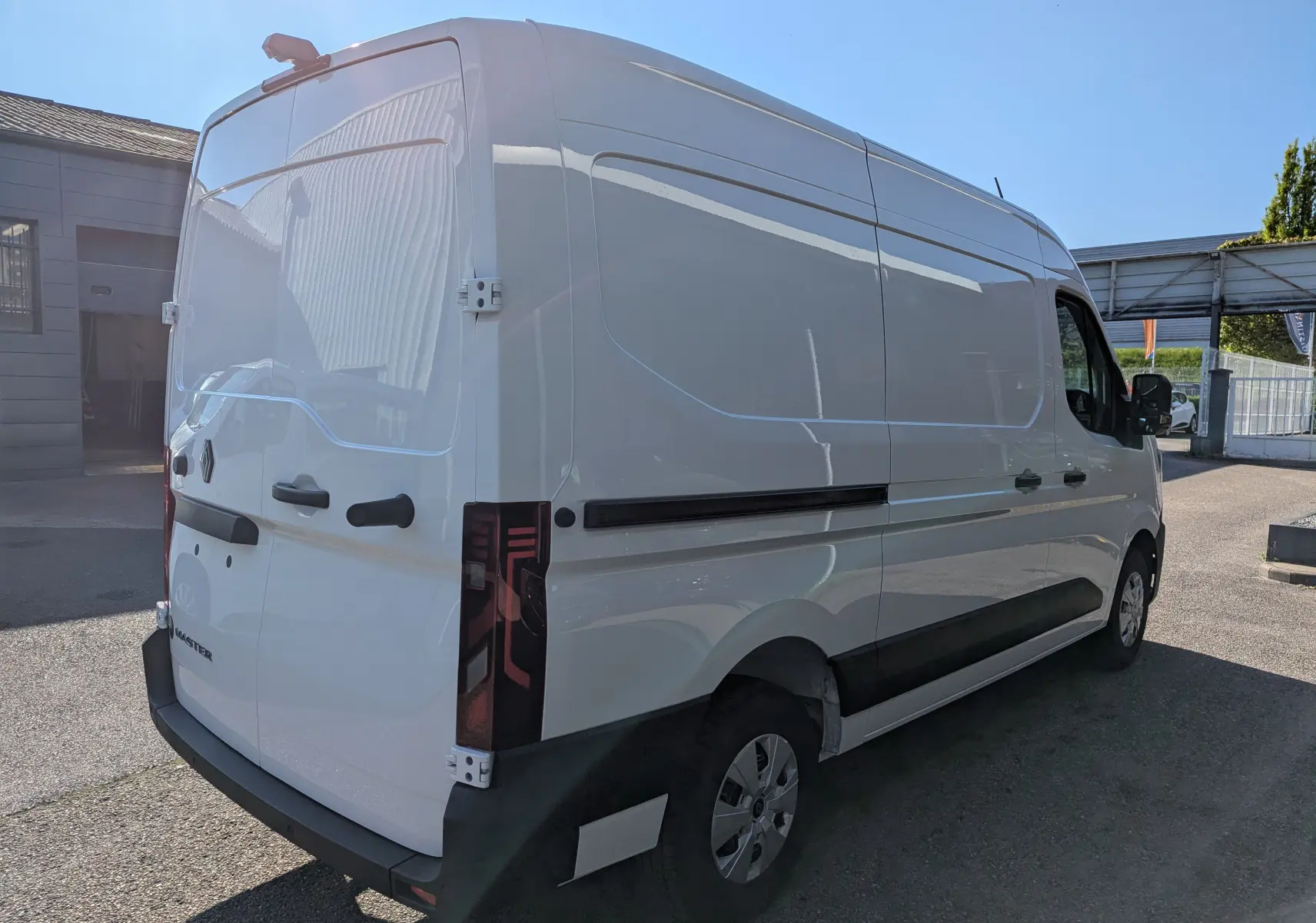 Vue 3/4 arrière droite d'un Renault Master blanc 2025, fourgon utilitaire avec feux arrière verticaux et poignées noires.
