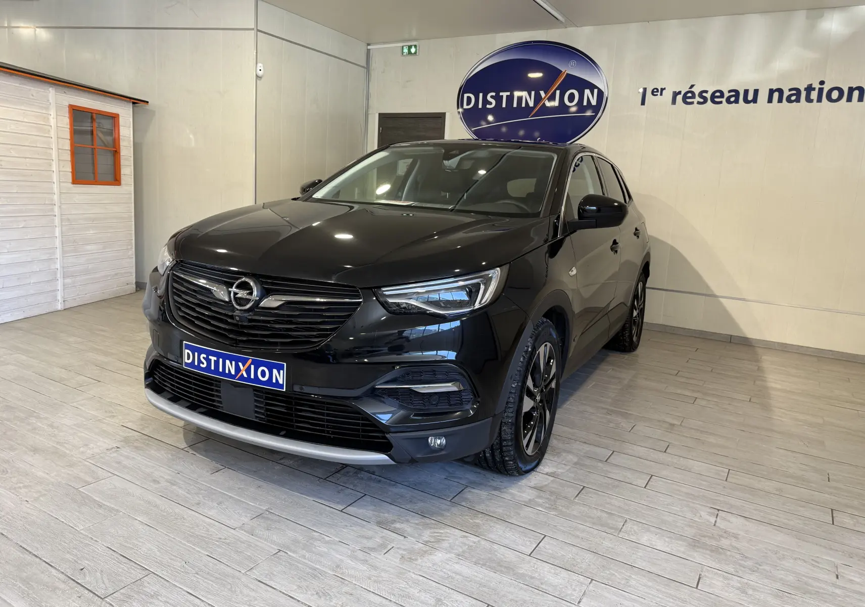 Opel Grandland X noir métal en 3/4 avant droit, SUV hybride avec jantes noires et calandre chromée showroom