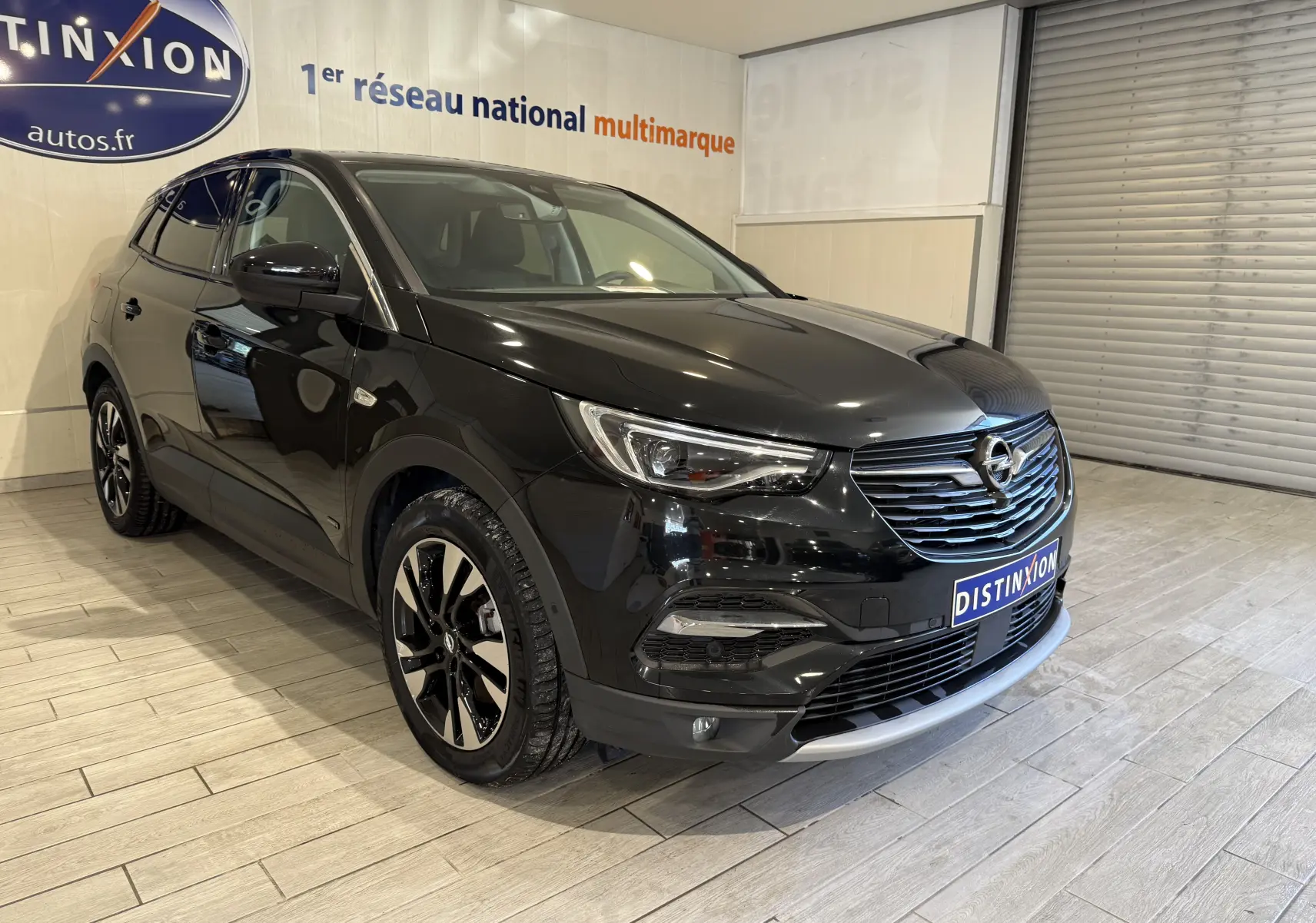 Opel Grandland X noir métal en 3/4 avant droit, avec jantes alliage et calandre chromée visible en showroom.