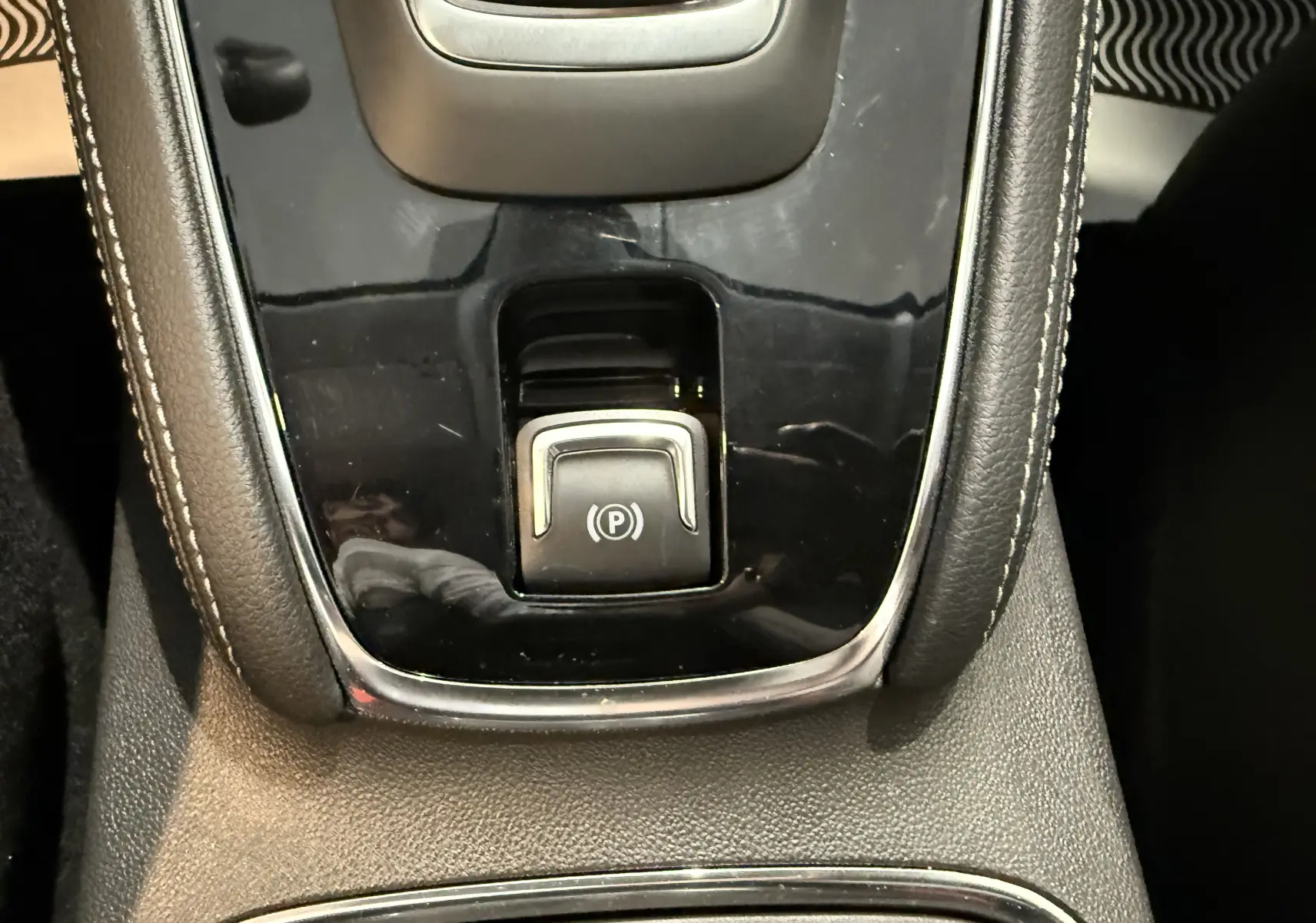 Gros plan sur le bouton de frein à main électronique au centre de la console d'une Opel Grandland X noire 2021.