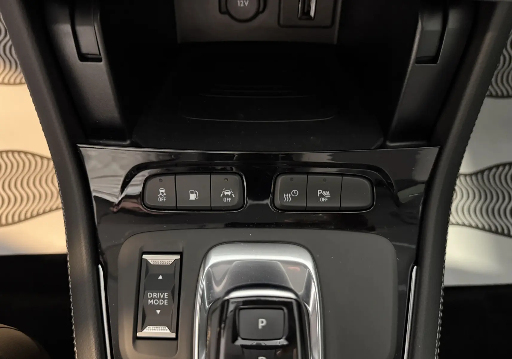 Vue rapprochée de la console centrale noire brillante de l'Opel Grandland X 1.6 Hybrid Turbo avec commandes Drive Mode et stationnement.
