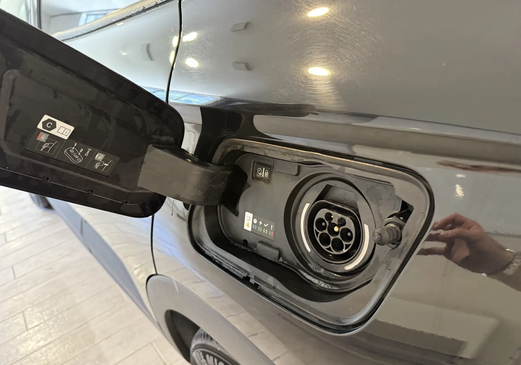 Prise de recharge ouverte côté gauche d'un Opel Grandland X noir métal hybride rechargeable, vue rapprochée sur la trappe.
