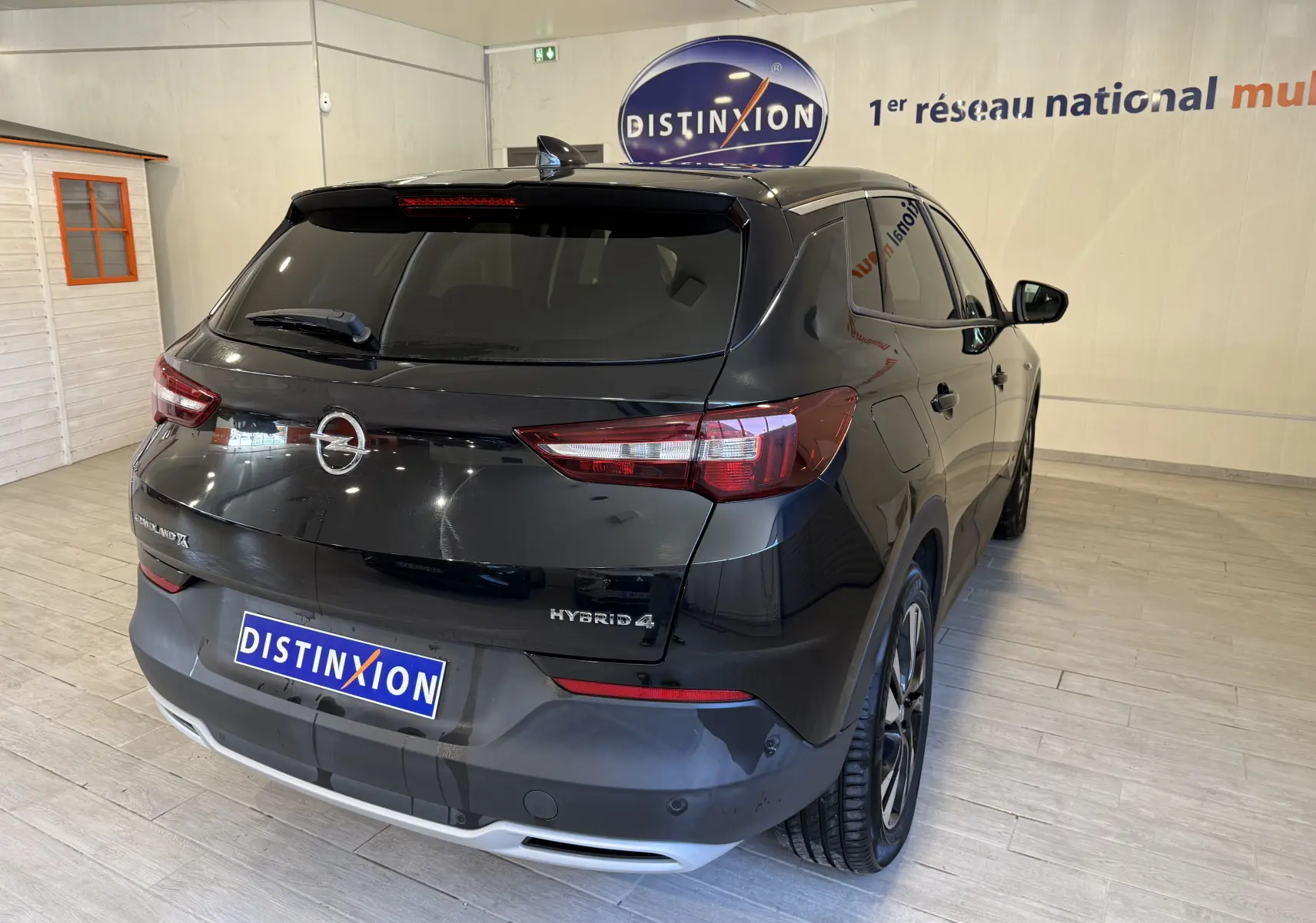 Vue 3/4 arrière droite d'un Opel Grandland X noir métal hybride rechargeable dans un showroom lumineux.