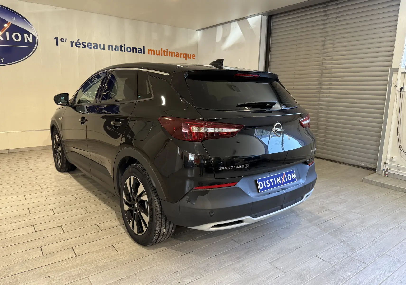 Vue 3/4 arrière droite d'un Opel Grandland X noir métal avec jantes alliage et feux arrière LED en intérieur showroom.