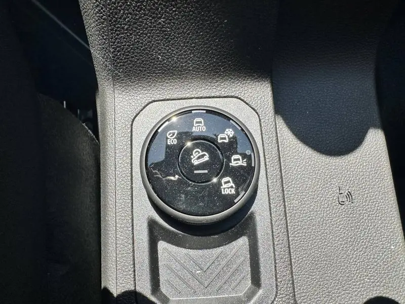 Gros plan sur la molette de sélection des modes de conduite du Dacia Duster blanc, intérieur noir texturé.