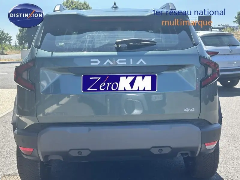 Vue arrière d'un Dacia Duster blanc Glacier 4x4 avec logo DACIA et plaque Zéro KM visible au soleil.