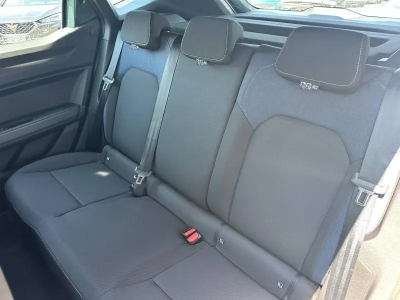 Vue latérale intérieure montrant la banquette arrière noire du Dacia Duster 2025 avec appuie-têtes et ceintures de sécurité.