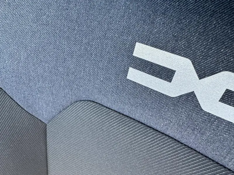 Détail du tissu bleu denim avec logo Dacia sur la banquette arrière du Dacia Duster blanc 2025.