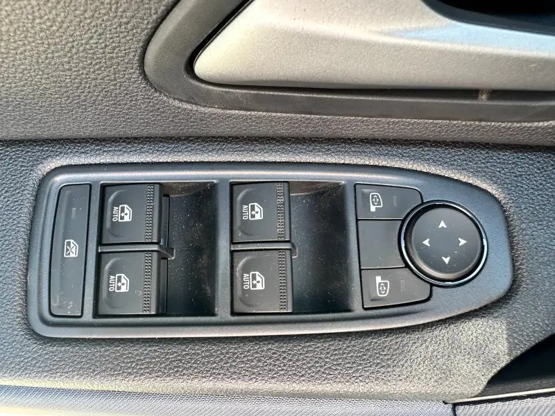 Commande des vitres électriques et réglage des rétroviseurs sur la porte côté conducteur du Dacia Duster blanc 2025.