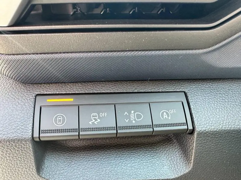 Boutons de commande du tableau de bord du Dacia Duster 2025, vue rapprochée avec éclairage orange sur le bouton de verrouillage central.