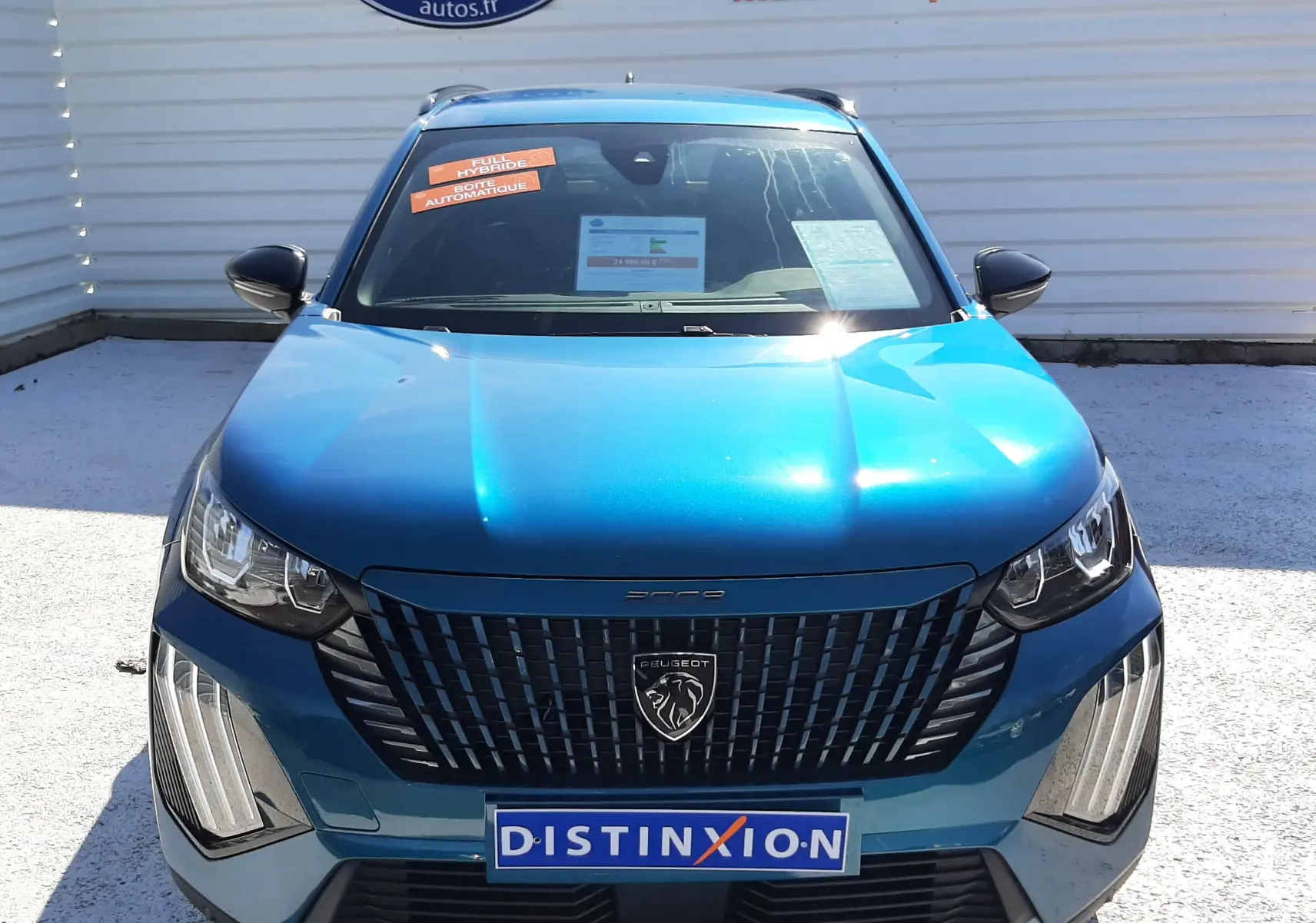 Vue frontale d'un Peugeot 2008 Hybrid 145 Allure bleu obsession, avec calandre noire et plaques Distinxion visibles.