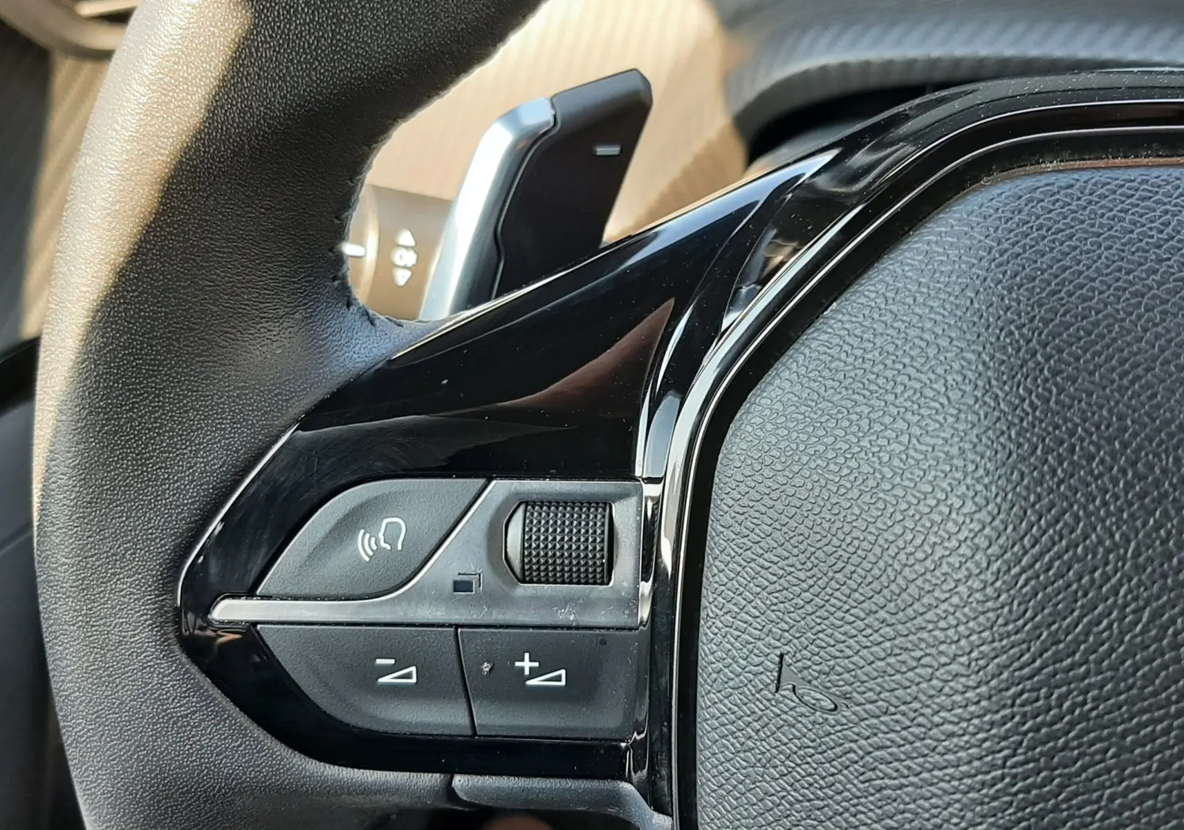 Gros plan sur la partie gauche du volant noir du Peugeot 2008 Hybrid 145 Allure 2025, avec commandes intégrées.