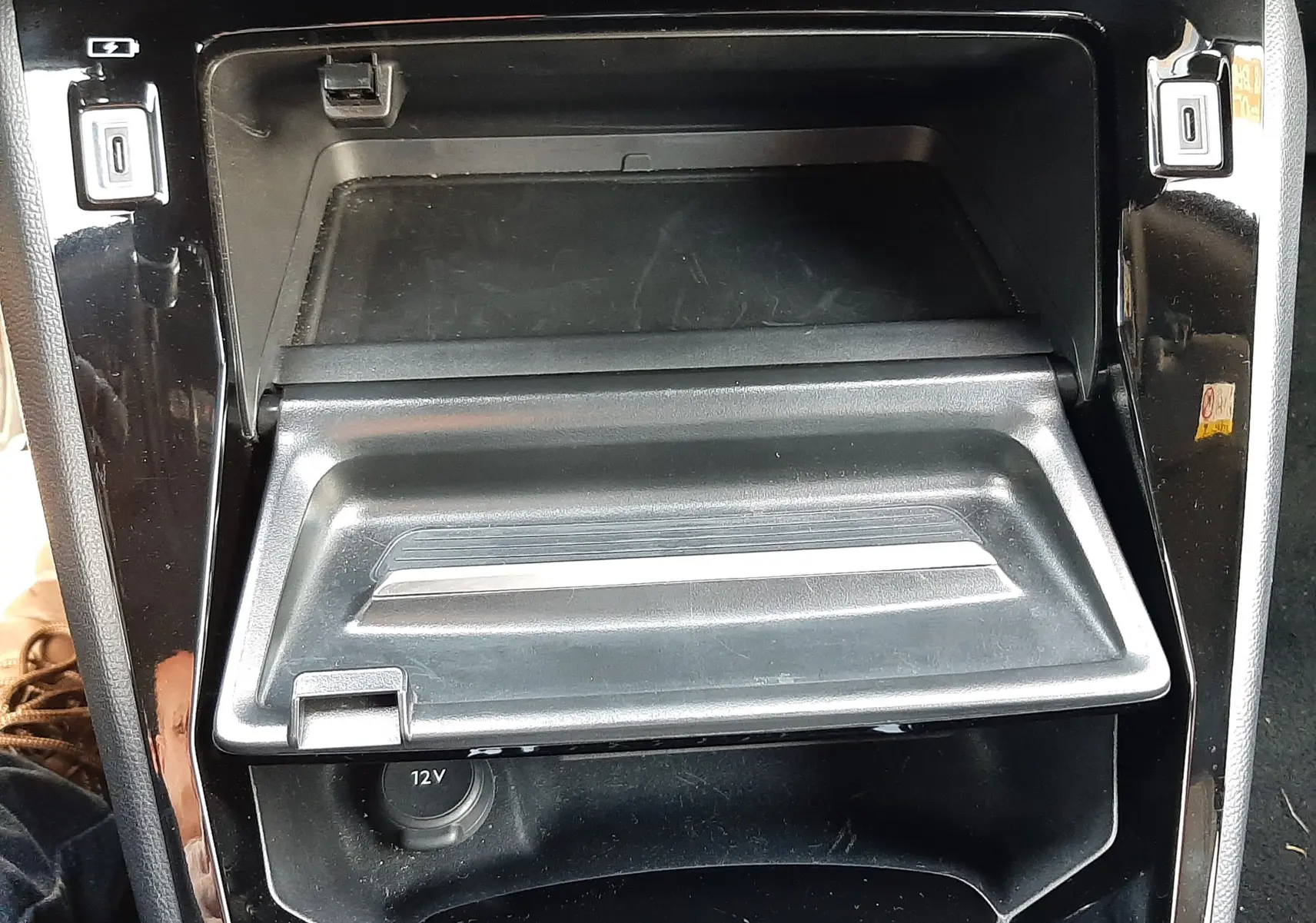 Gros plan sur la console centrale noire du Peugeot 2008 Hybrid 145 Allure, montrant le compartiment ouvert et prises USB.