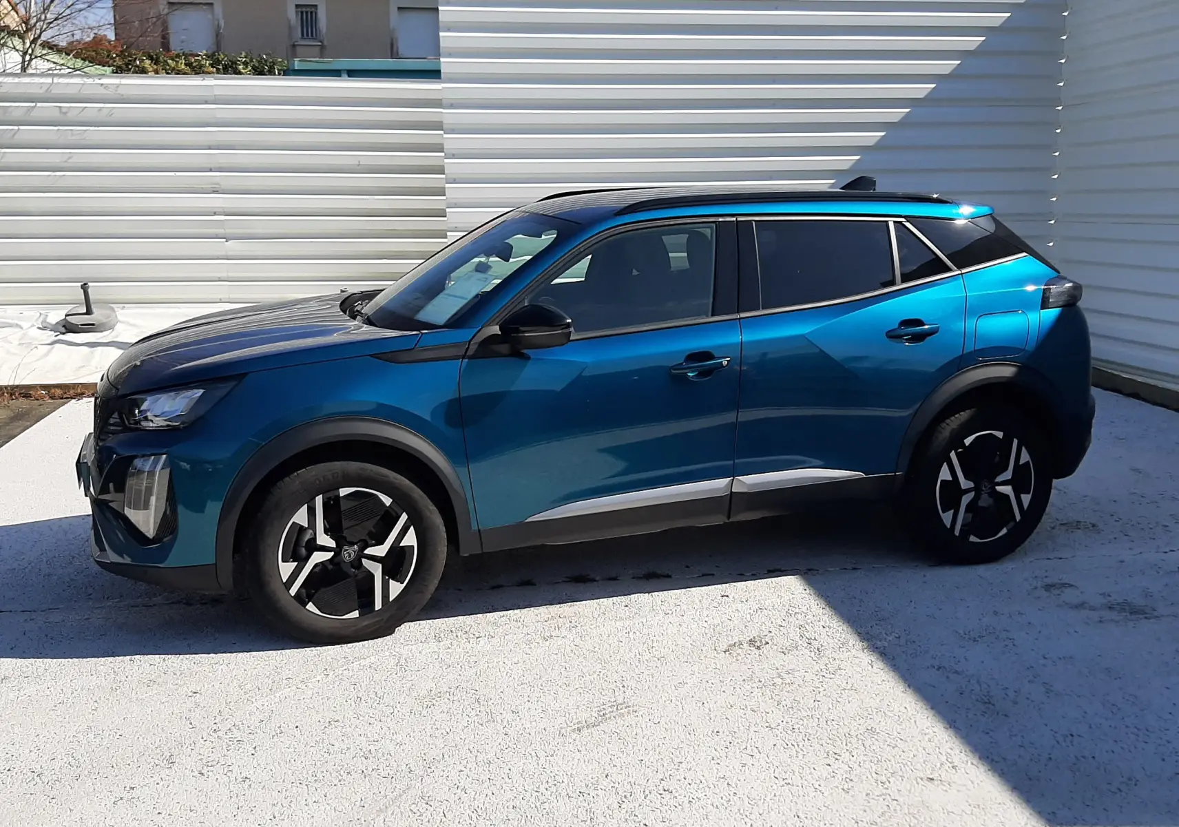 Peugeot 2008 Hybrid 145 Allure en bleu obsession, vue de profil côté gauche, avec toit noir et jantes bicolores.