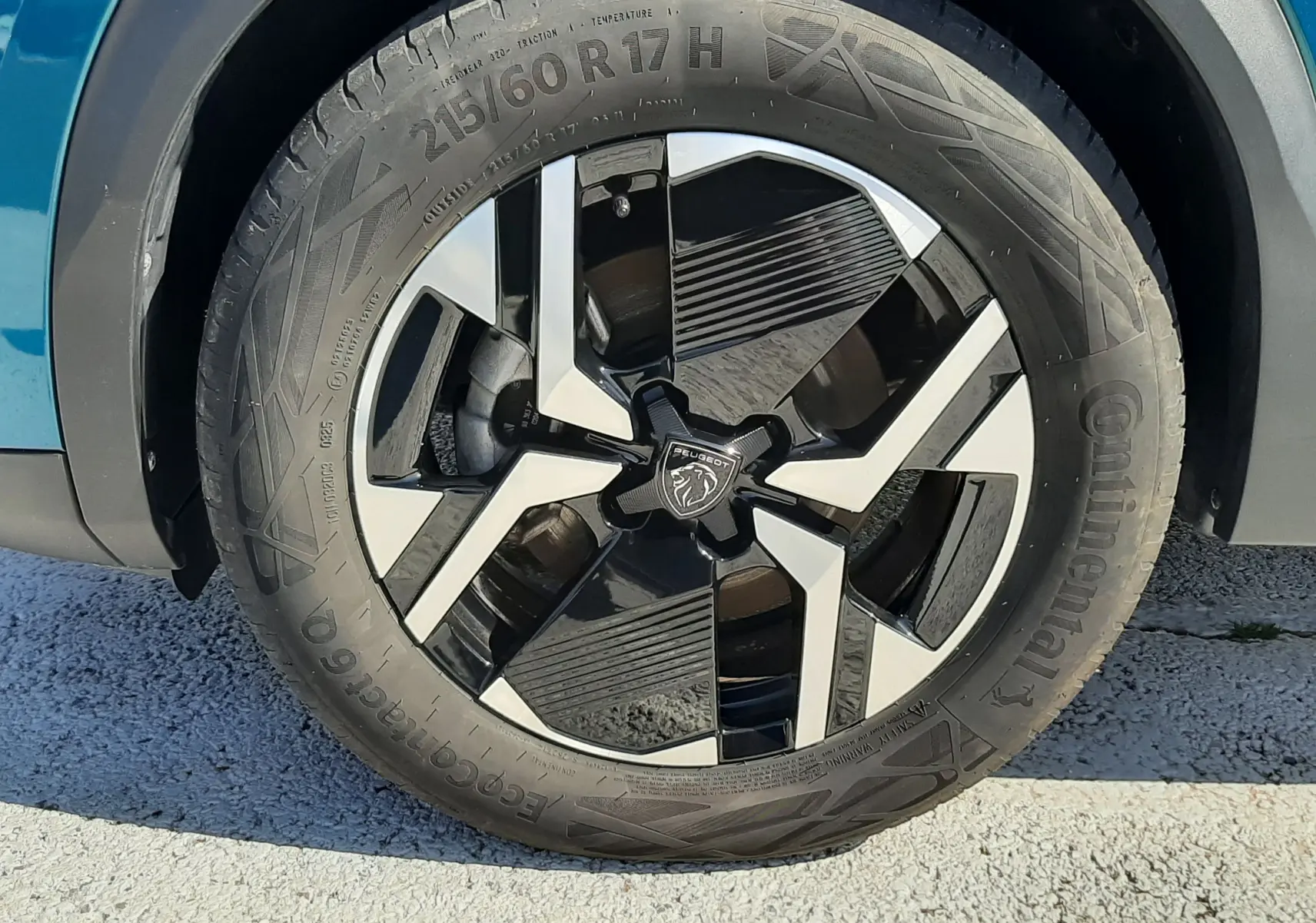 Gros plan sur la roue avant droite d’un Peugeot 2008 Bleu Obsession, jante alliage bicolore au design moderne.