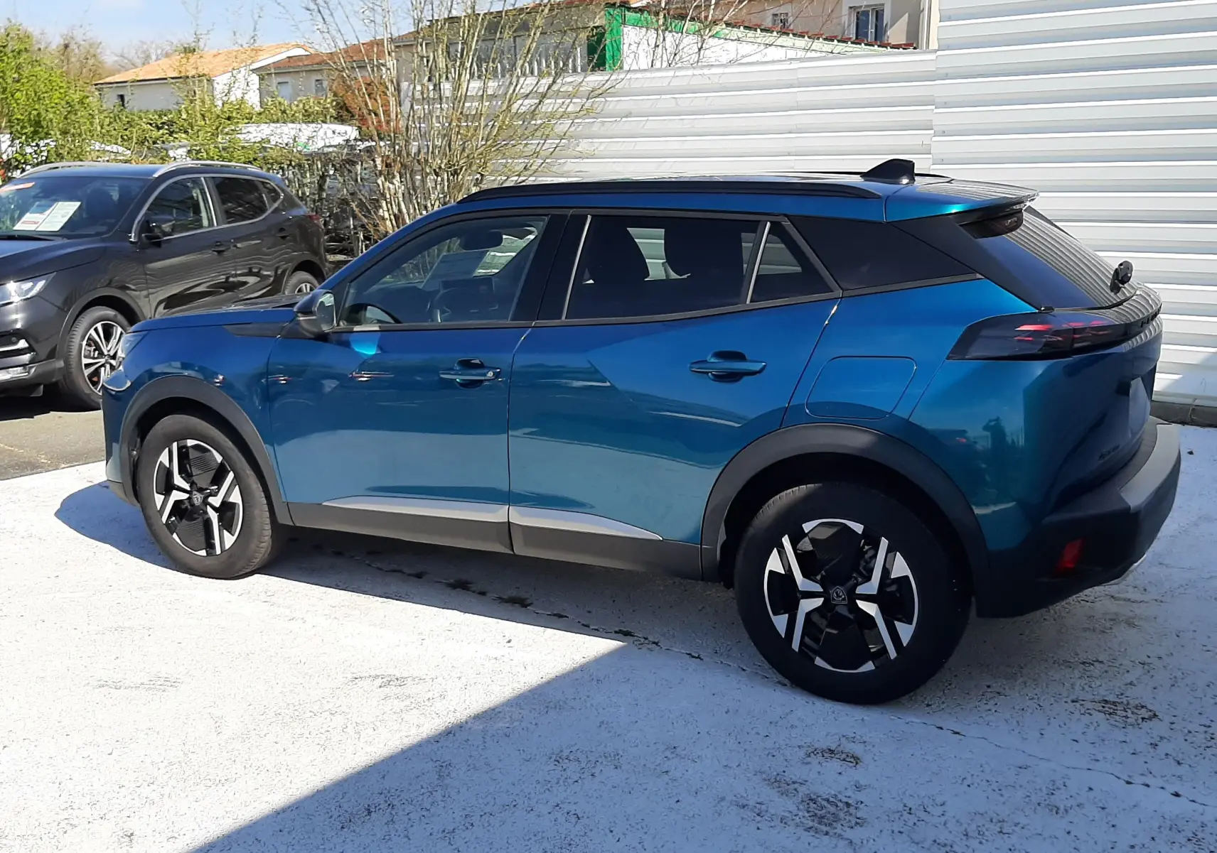 Peugeot 2008 Hybrid 145 Allure bleu obsession vue de profil côté gauche, toit noir et jantes bicolores distinctives.