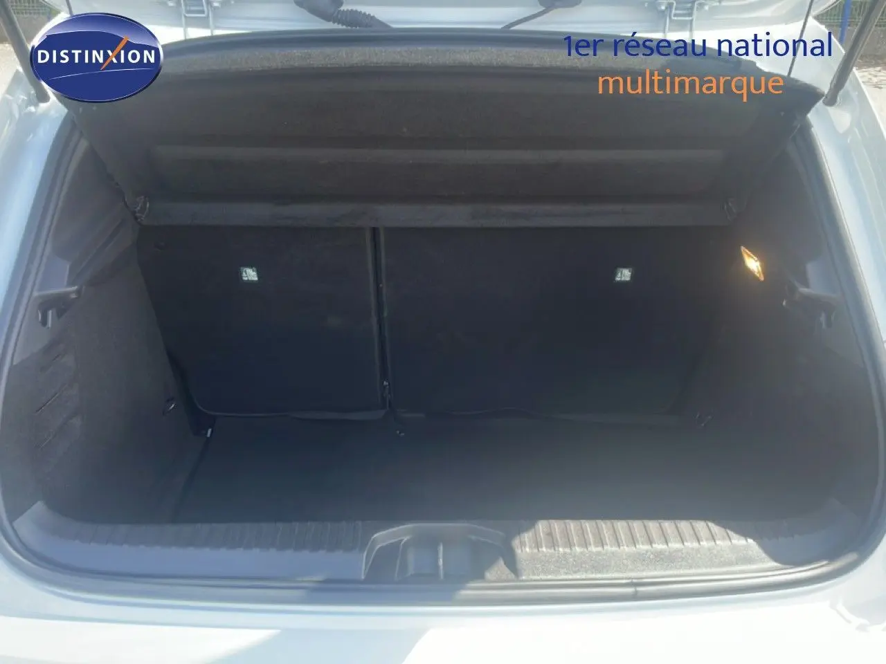 Coffre ouvert de la Renault Clio blanche 2025, vue arrière montrant l’espace de chargement vide et l’éclairage intérieur.