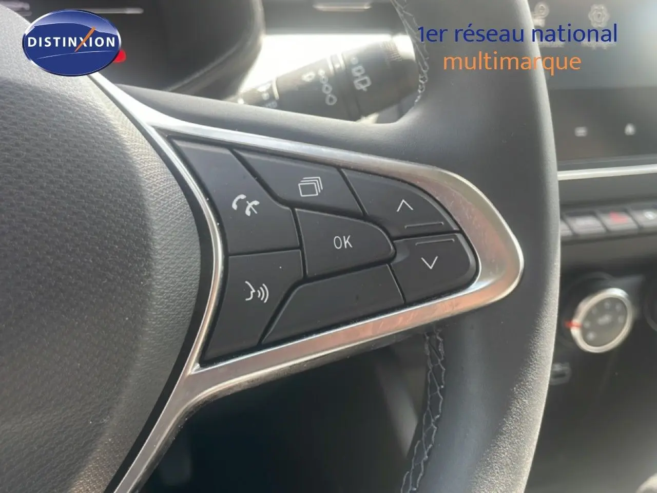 Gros plan sur les commandes multifonctions à droite du volant en cuir noir d'une Renault Clio blanche 2025.