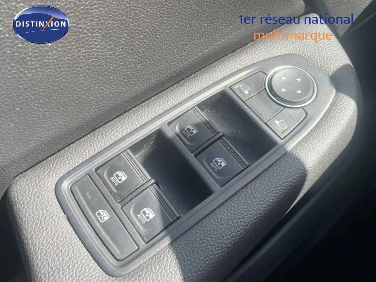 Gros plan sur les commandes de lève-vitres et rétroviseurs côté conducteur d'une Renault Clio blanche 2025.