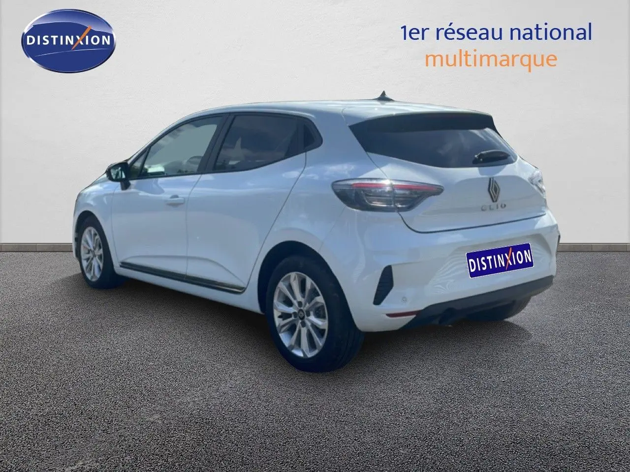 Renault Clio blanche vue 3/4 arrière droit, avec jantes alliage et vitres teintées, sur fond neutre intérieur.