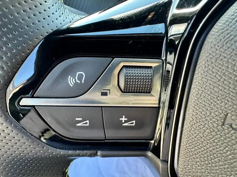 Gros plan sur les commandes du volant cuir perforé du Peugeot 2008 GT 2022, boutons de volume et commande vocale.