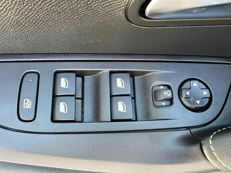 Commandes des vitres électriques et réglages des rétroviseurs sur la porte côté conducteur d'une Peugeot 2008 gris Artense.