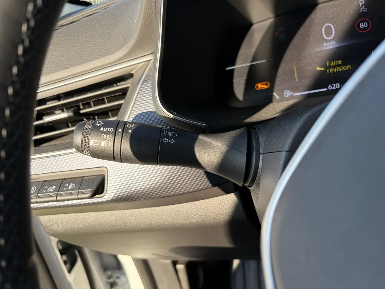 Détail intérieur du commodo d'éclairage à gauche du volant dans un Renault Arkana blanc Glacier 2025.