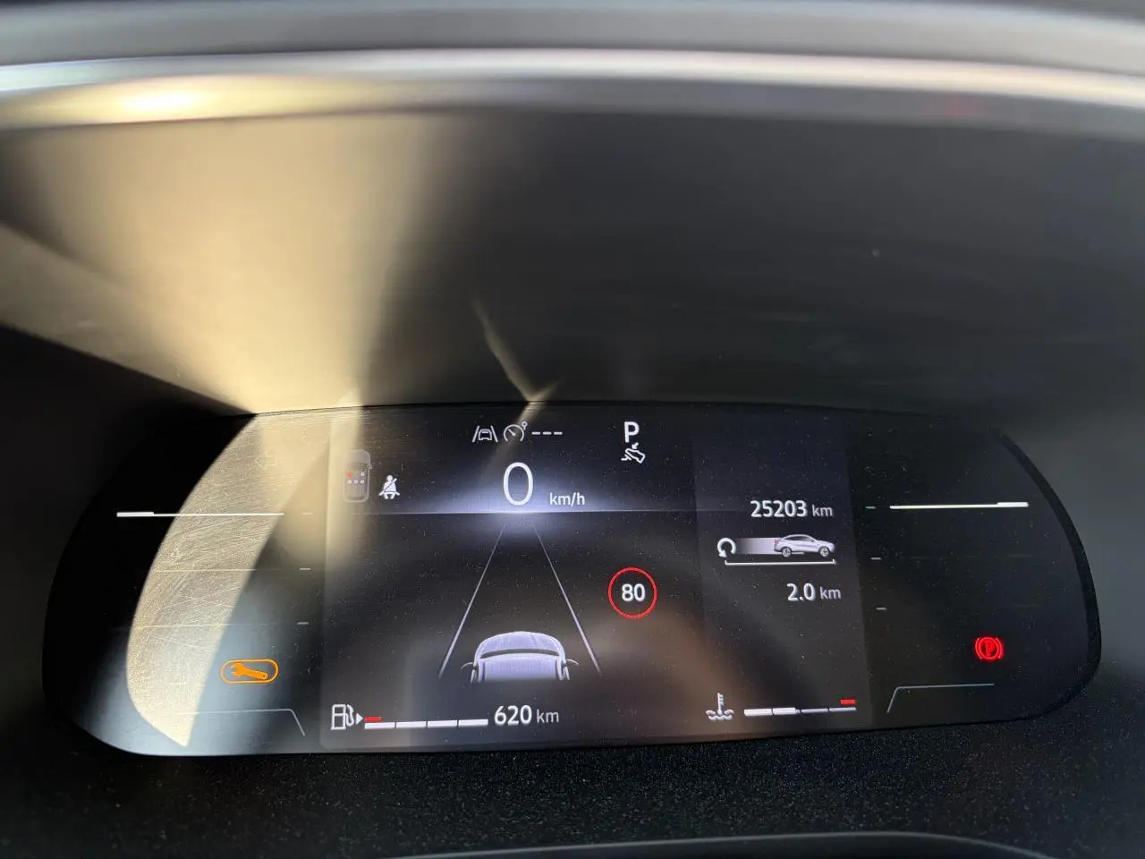 Tableau de bord numérique du Renault Arkana 2025 affichant vitesse, autonomie et alertes, vue frontale rapprochée.