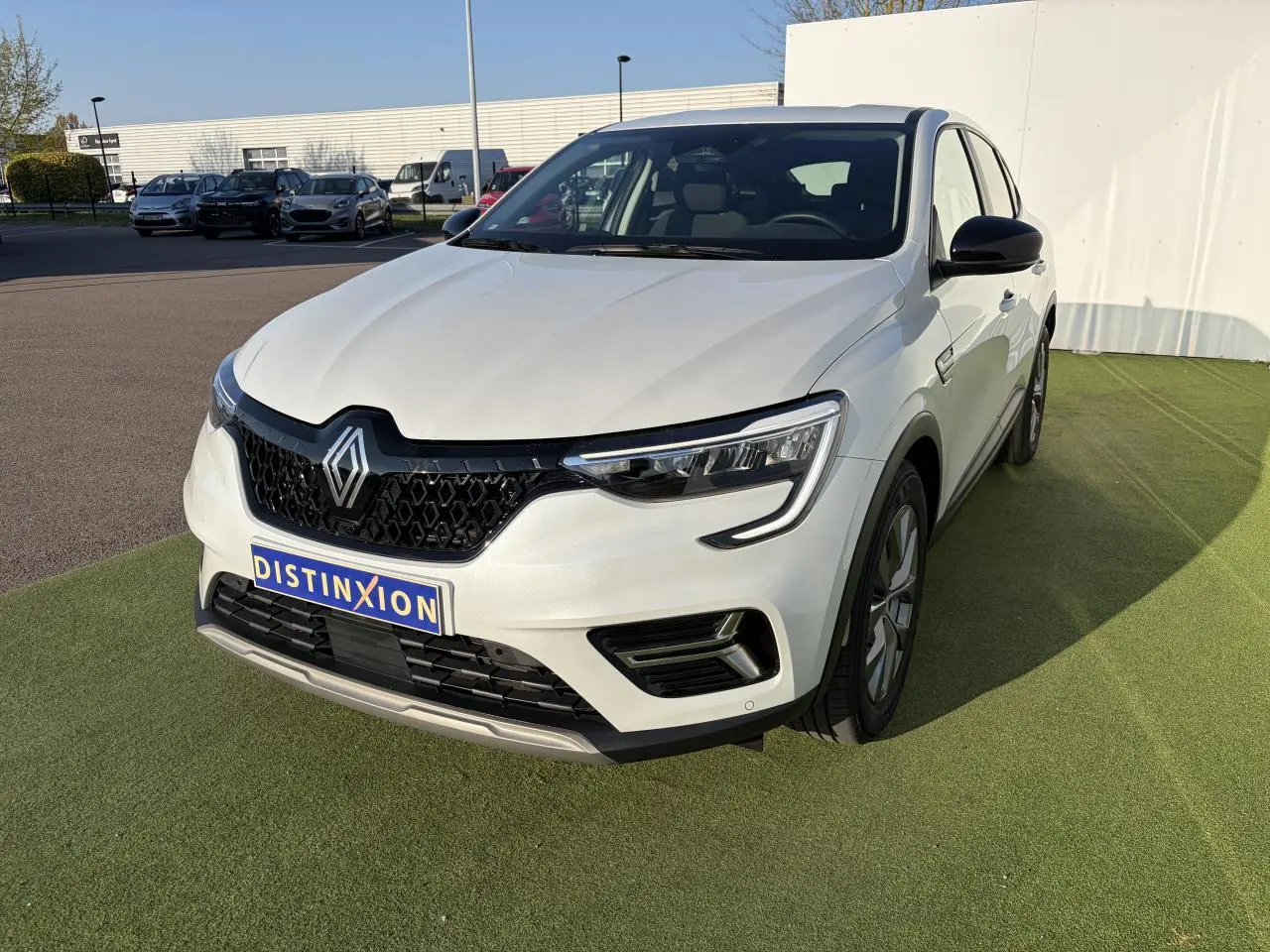 Renault Arkana blanc glacier en 3/4 avant droit avec calandre noire et jantes alliage grises 17 pouces.