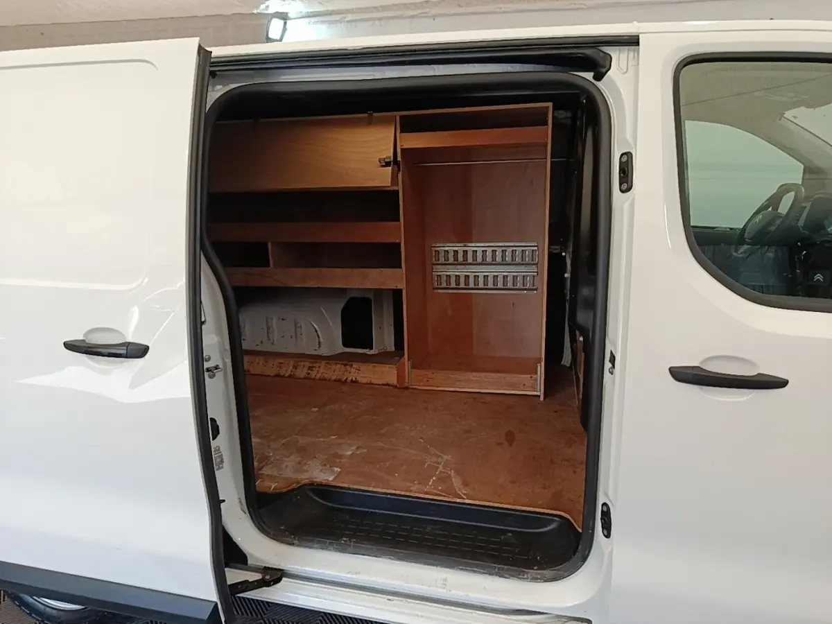 Vue latérale gauche d’un Citroën Jumpy blanc 2021 avec porte coulissante ouverte montrant l’aménagement intérieur en bois.