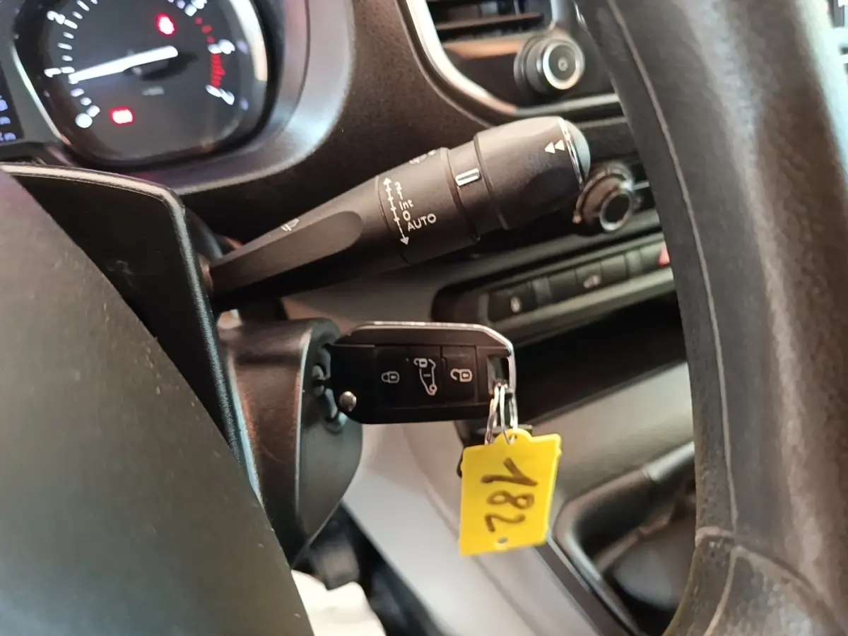 Gros plan sur la clé insérée dans le contact d'un Citroën Jumpy blanc, avec tableau de bord et commandes visibles.