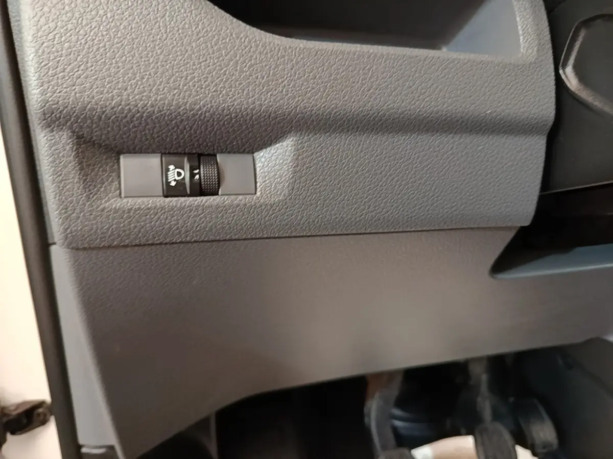 Détail intérieur du tableau de bord côté conducteur du Citroën Jumpy blanc, bouton de réglage des phares visible.